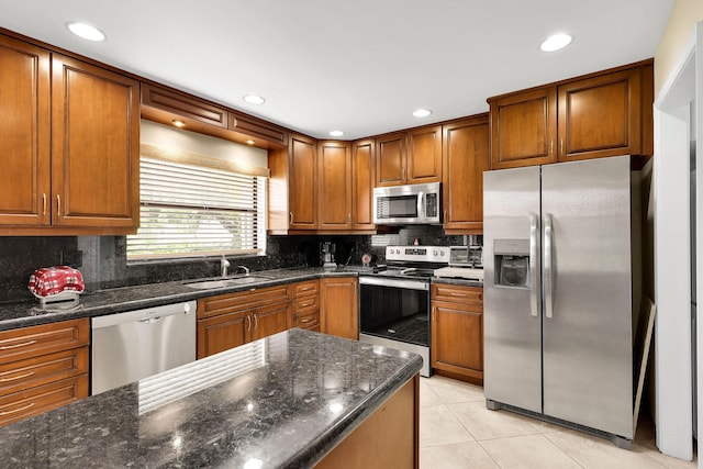 kitchen featuring dark stone counters, light tile patterned floors, tasteful backsplash, sink, and appliances with stainless steel finishes