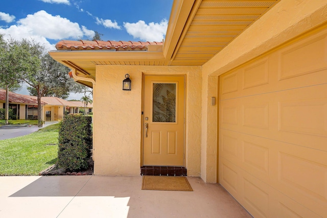 entrance to property featuring a garage and a yard