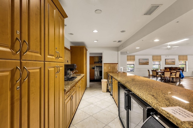 kitchen featuring ceiling fan, stainless steel range, light stone counters, and light tile patterned flooring