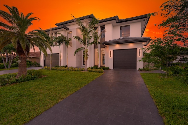 view of front of house with stucco siding, driveway, and a lawn