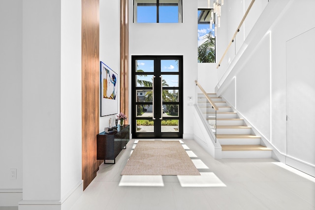 entryway featuring french doors, a towering ceiling, and stairs