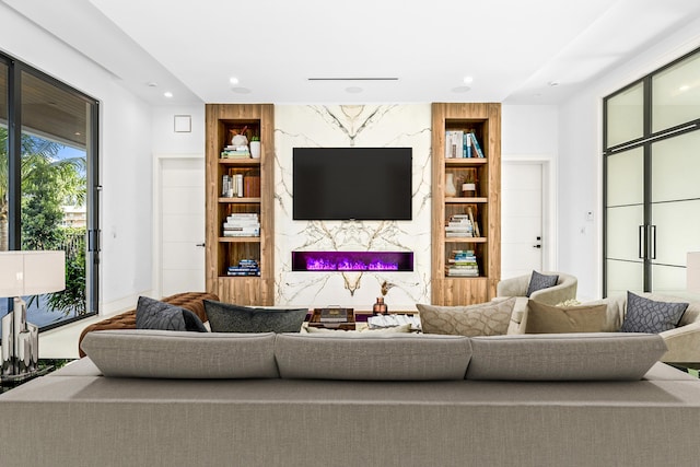 living area with built in shelves, a high end fireplace, an accent wall, and recessed lighting