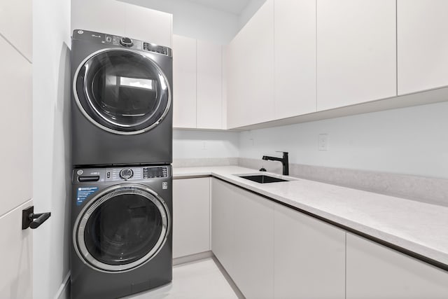 washroom with a sink, cabinet space, and stacked washer / dryer