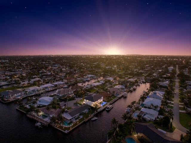 aerial view at dusk featuring a water view and a residential view