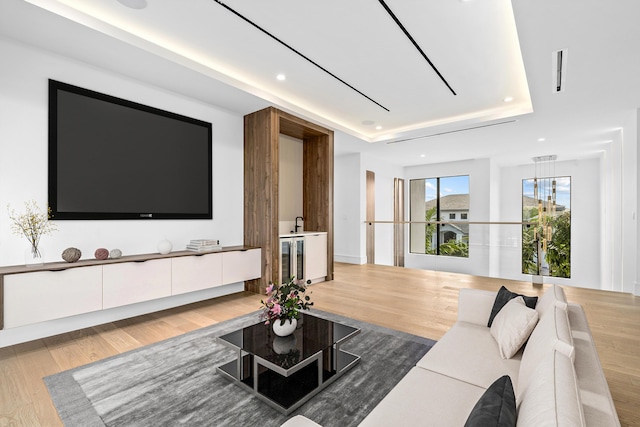 living area with light wood-style flooring, a raised ceiling, and recessed lighting