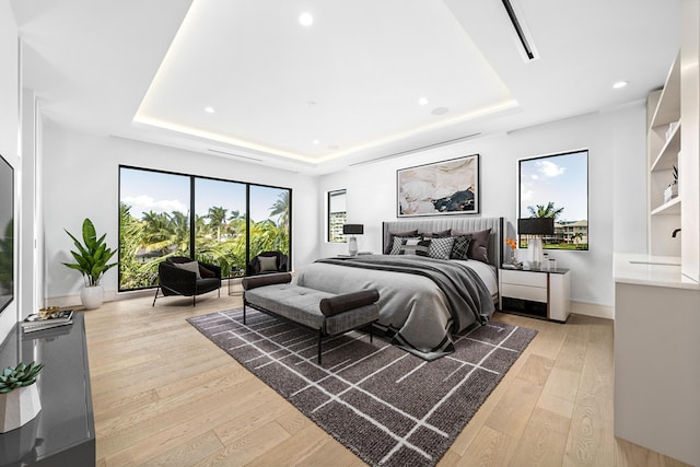 bedroom featuring light wood-style flooring, baseboards, and a raised ceiling