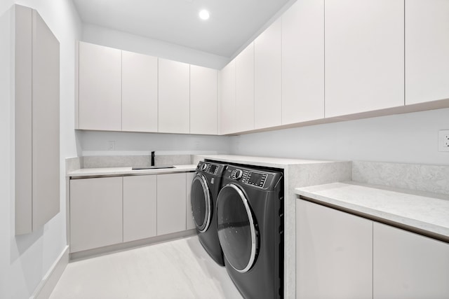 clothes washing area with a sink, washing machine and dryer, cabinet space, and recessed lighting