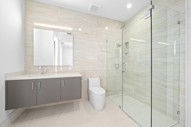 bathroom with visible vents, toilet, vanity, a shower stall, and tile walls