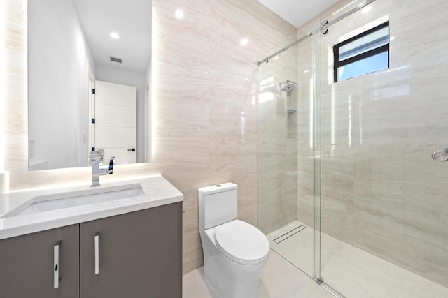 bathroom with toilet, vanity, visible vents, tile walls, and a shower stall