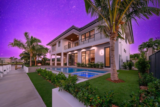 pool at dusk with a patio, fence private yard, an in ground hot tub, a yard, and an outdoor pool