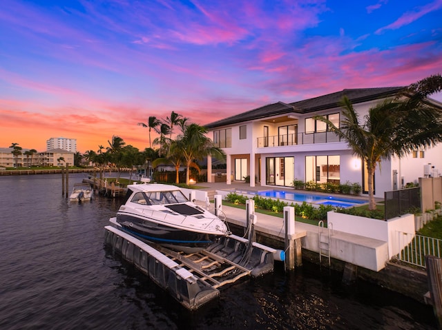 dock area featuring an outdoor pool, a patio, a balcony, boat lift, and a water view