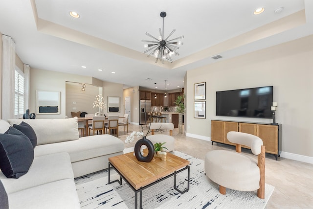 living room featuring a raised ceiling, light tile patterned flooring, and a notable chandelier