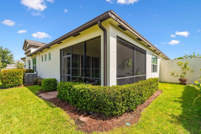 view of side of home with a sunroom, a yard, and cooling unit