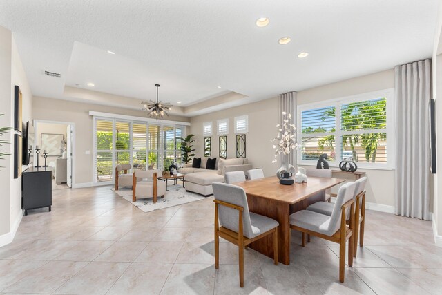 tiled dining room featuring a tray ceiling and a notable chandelier