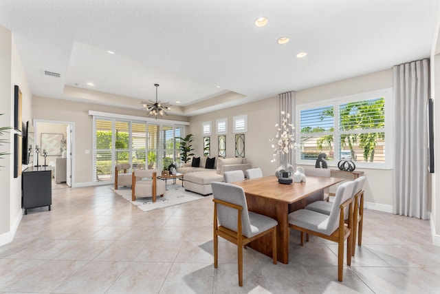 tiled dining area featuring a notable chandelier and a raised ceiling