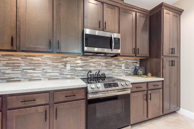 kitchen with light stone countertops, light tile patterned floors, tasteful backsplash, dark brown cabinetry, and stainless steel appliances