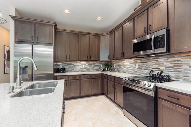 kitchen with decorative backsplash, appliances with stainless steel finishes, dark brown cabinets, sink, and light tile patterned floors