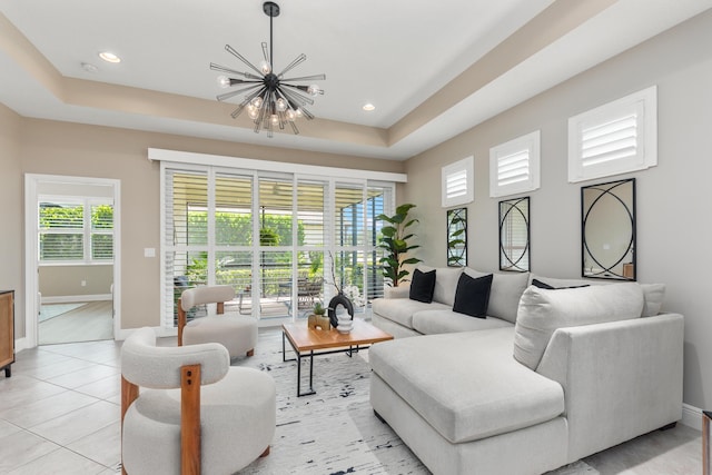 tiled living room featuring a raised ceiling and an inviting chandelier