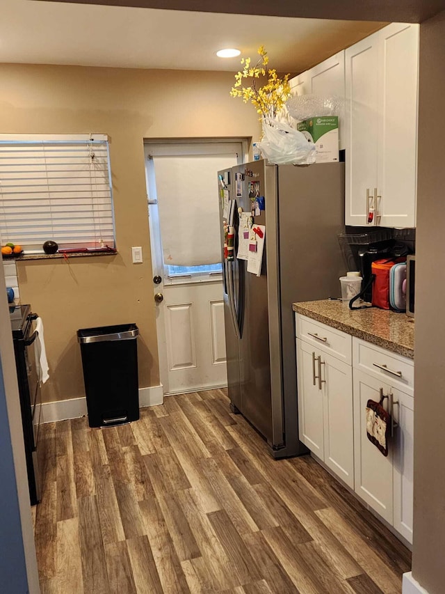 kitchen with stone counters, white cabinetry, dark hardwood / wood-style floors, and appliances with stainless steel finishes