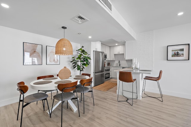 dining space with sink and light hardwood / wood-style floors