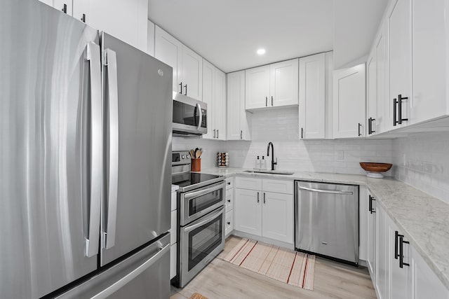 kitchen featuring light wood-type flooring, appliances with stainless steel finishes, sink, and white cabinets