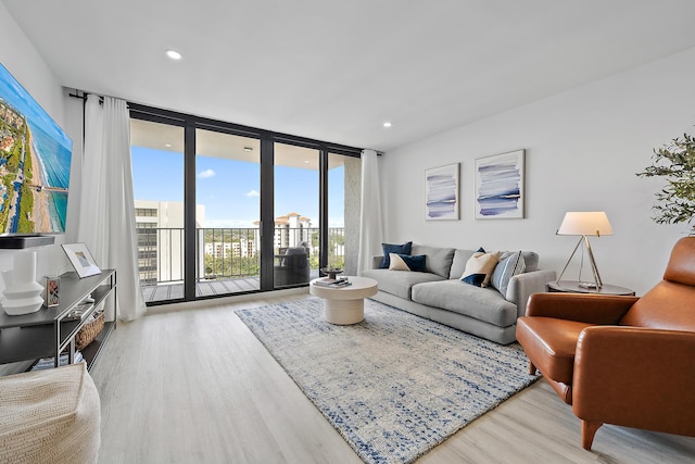 living room featuring light wood-type flooring and a wall of windows