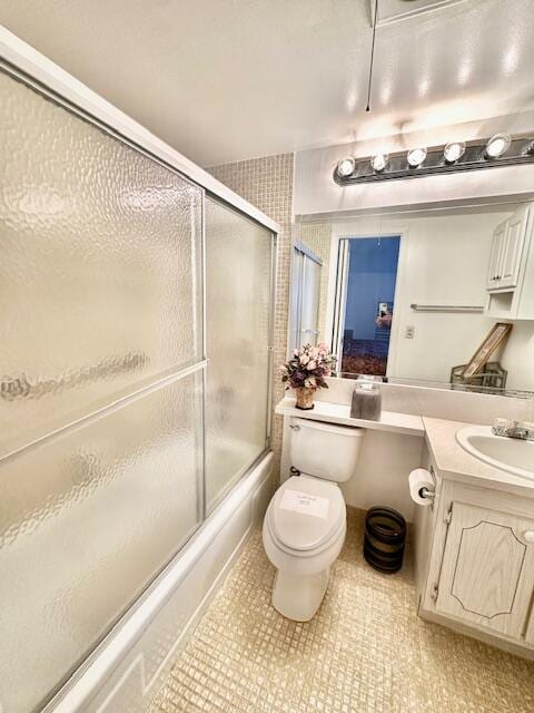 full bathroom featuring vanity, combined bath / shower with glass door, tile patterned flooring, and toilet