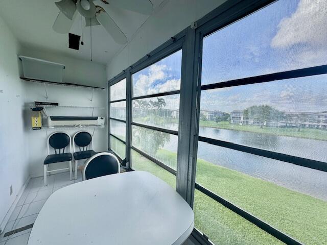 sunroom featuring ceiling fan and a water view