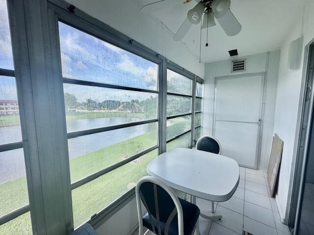 sunroom / solarium with a water view and ceiling fan