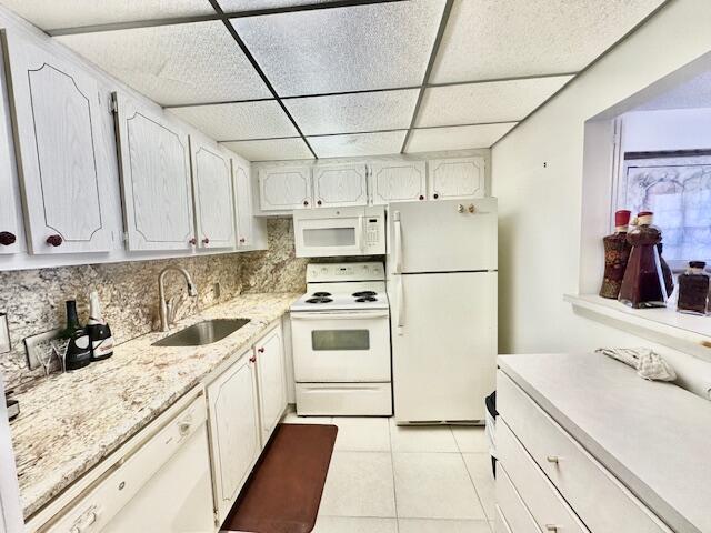 kitchen featuring sink, tasteful backsplash, light tile patterned floors, white cabinetry, and white appliances