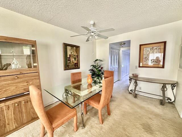 carpeted dining area featuring a textured ceiling and ceiling fan