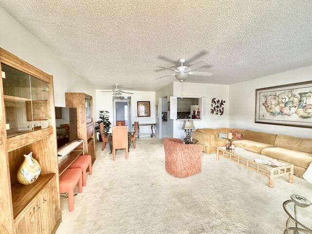 carpeted living room featuring ceiling fan and a textured ceiling