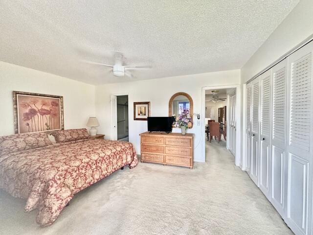 bedroom with a closet, carpet, a textured ceiling, and ceiling fan