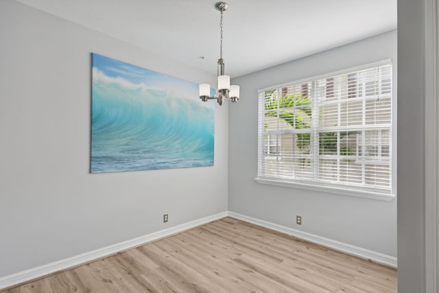 unfurnished room featuring light hardwood / wood-style floors and a chandelier