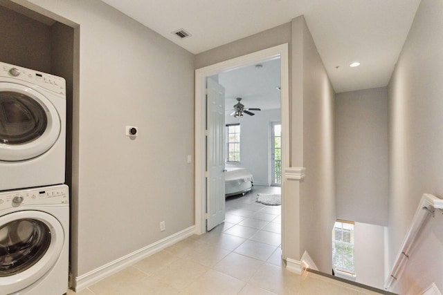 clothes washing area featuring light tile patterned floors, ceiling fan, and stacked washer / drying machine