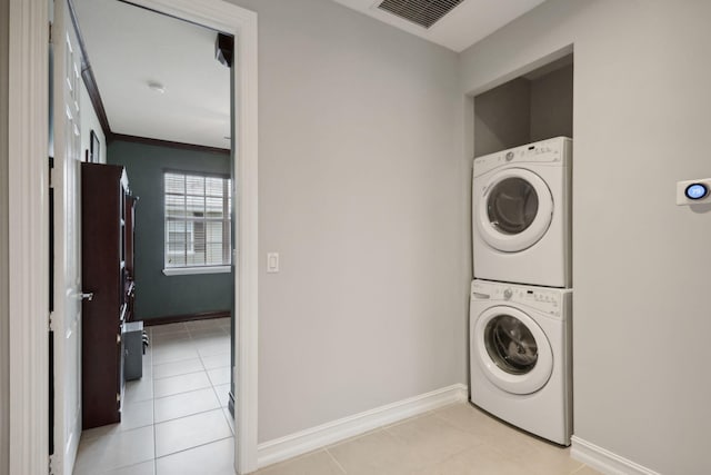 laundry room featuring light tile patterned floors, stacked washer and clothes dryer, and ornamental molding