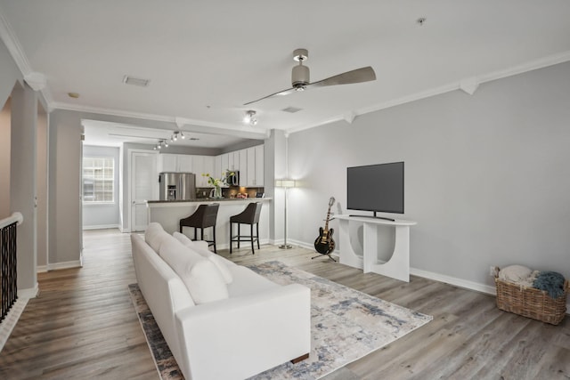 living room featuring light hardwood / wood-style floors, ceiling fan, and ornamental molding