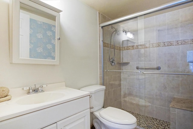 bathroom featuring vanity, toilet, and a shower with shower door