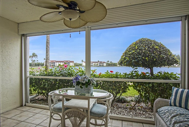 sunroom / solarium featuring ceiling fan and a water view