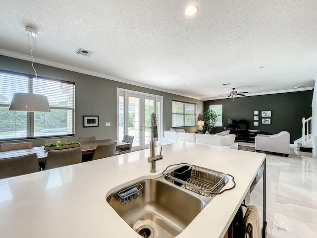 kitchen with ceiling fan, a textured ceiling, sink, and ornamental molding