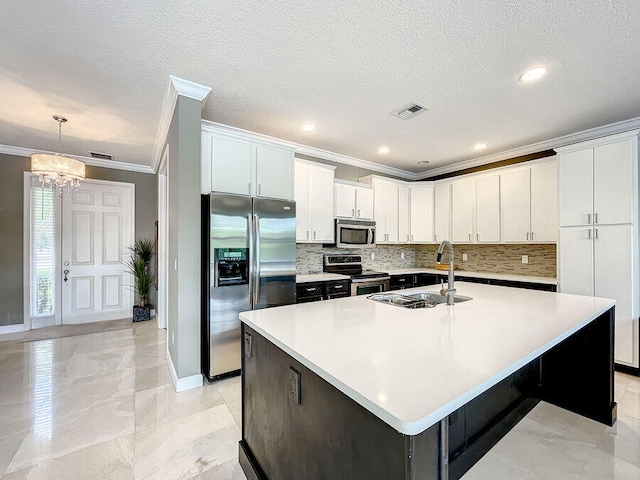 kitchen featuring stainless steel appliances, a center island with sink, hanging light fixtures, sink, and white cabinetry