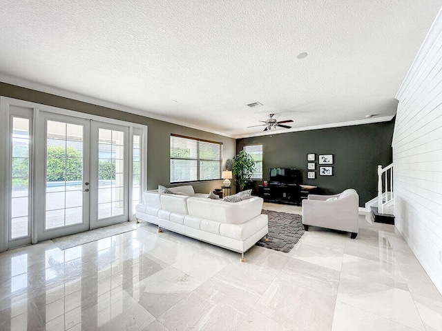 living room with ceiling fan, a textured ceiling, french doors, and ornamental molding