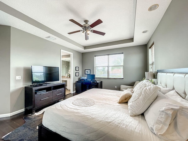 bedroom with dark wood-type flooring, ceiling fan, connected bathroom, and a textured ceiling