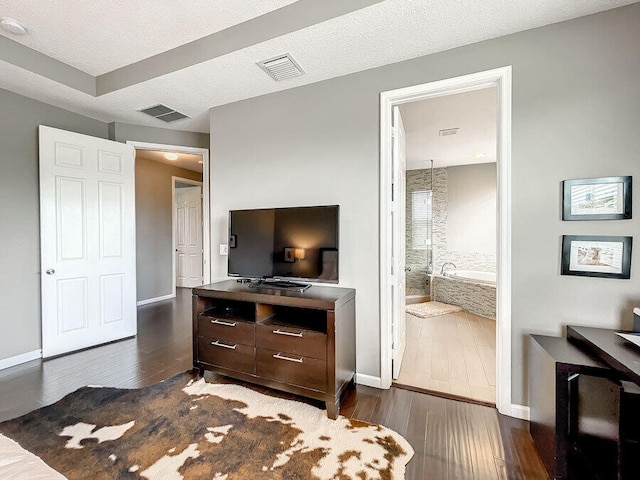 bedroom featuring a textured ceiling, dark hardwood / wood-style floors, and ensuite bathroom