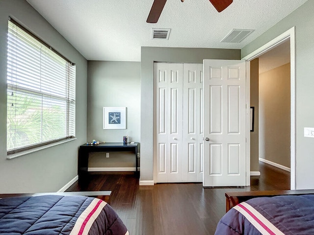 bedroom featuring ceiling fan, dark hardwood / wood-style floors, a closet, and a textured ceiling