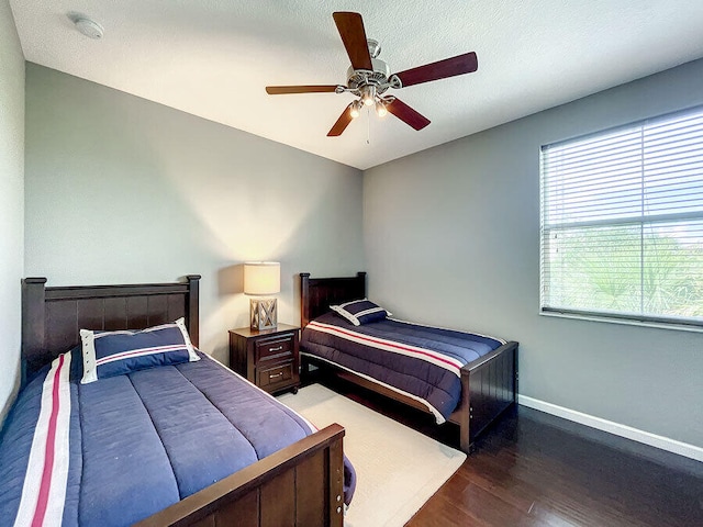 bedroom with dark wood-type flooring, ceiling fan, and a textured ceiling