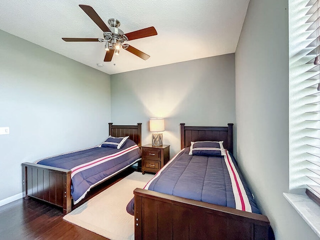 bedroom featuring dark hardwood / wood-style flooring, a textured ceiling, and ceiling fan