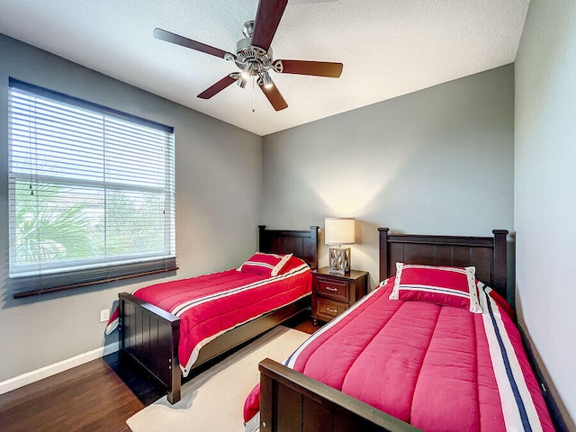 bedroom featuring dark wood-type flooring, a textured ceiling, and ceiling fan