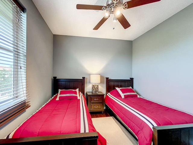 bedroom with hardwood / wood-style floors, ceiling fan, and a textured ceiling