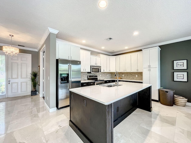 kitchen featuring ornamental molding, white cabinetry, appliances with stainless steel finishes, sink, and a kitchen island with sink